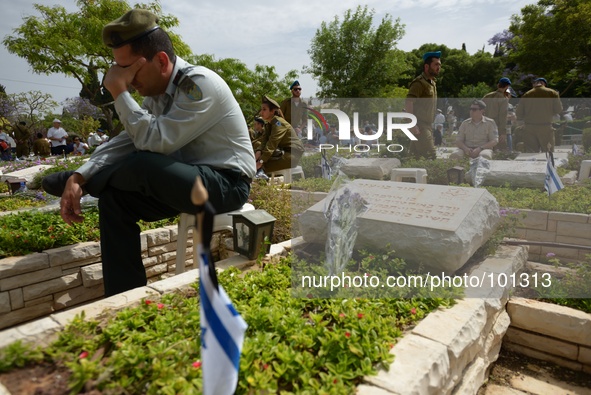 TEL AVIV, ISRAEL - MAY 05: An Israeli soldier reacts as he sits by the grave of a fallen Israeli soldier at the military cemetery Kiryat Sha...
