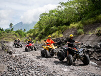Tourists ride an all-terrain vehicle near the Mayon Volcano which remains under alert level 3, in Legazpi, Albay province, Philippines, June...