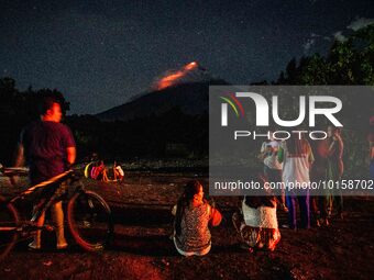 People watch as lava and ashes flow from the Mayon Volcano which remains under alert level 3, in Legazpi, Albay province, Philippines, on Ju...
