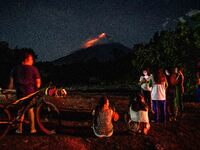 People watch as lava and ashes flow from the Mayon Volcano which remains under alert level 3, in Legazpi, Albay province, Philippines, on Ju...