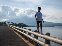 A boy walks on a guard rail at a bridge overlooking the Mayon Volcano which remains under alert level 3, in Legazpi, Albay province, Philipp...