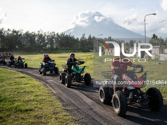Tourists ride an all-terrain vehicle on a trail overlooking the Mayon Volcano which remains under alert level 3, in Legazpi, Albay province,...