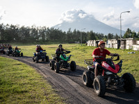 Tourists ride an all-terrain vehicle on a trail overlooking the Mayon Volcano which remains under alert level 3, in Legazpi, Albay province,...