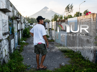 A man visits a cemetery overlooking the Mayon Volcano which remains under alert level 3, in Legazpi, Albay province, Philippines, on June 13...