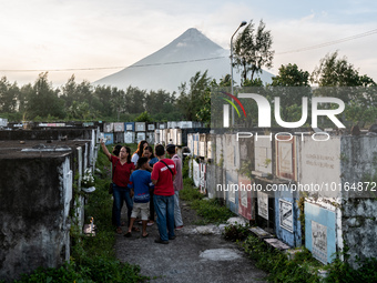 A family visits a cemetery overlooking the Mayon Volcano which remains under alert level 3, in Legazpi, Albay province, Philippines, on June...
