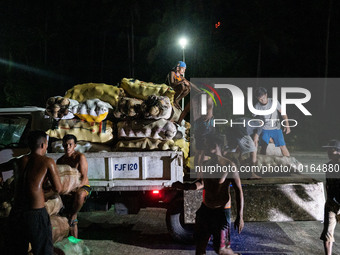 Workers load a truck with sacks of coconuts as the Mayon Volcano remains under alert level 3, in Legazpi, Albay province, Philippines, on Ju...
