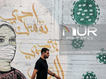 A Palestinian man walks past street art showing a Covid-19 coronavirus in Gaza City, on August 14, 2023. The number of new Covid-19 cases re...