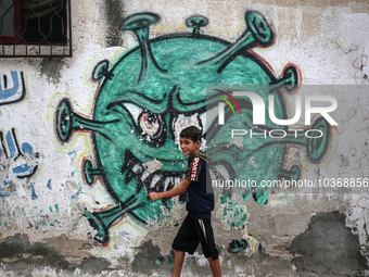A Palestinian boy walks past street art showing a Covid-19 coronavirus in Gaza City, on August 14, 2023. The number of new Covid-19 cases re...