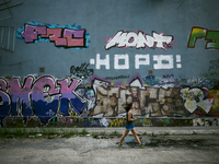 Ukraine - Odessa - Daily life - A young woman walks in front of a wall with Graffiti, in a abandoned street, Odessa, Ukraine, Thursday, Mai...