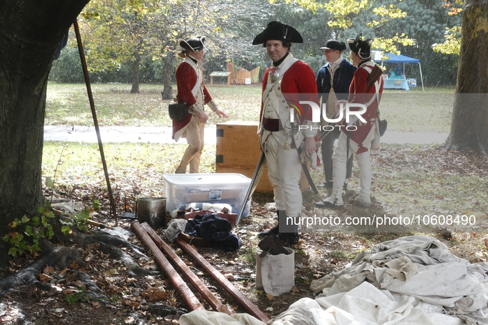 Historic reenactors in British Red Coats and Continental Blue Coats attire pause during a sudden downpour as the Revolutionary Germantown Fe...