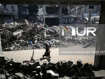 Palestinians are walking amid the rubble of destroyed buildings in Bureij camp in the central Gaza Strip on November 30, 2023, during a truc...