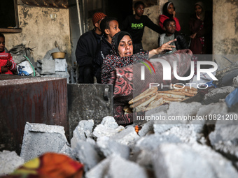 A Palestinian woman is baking traditional bread inside her damaged home in Bureij camp in the central Gaza Strip on November 30, 2023, amid...