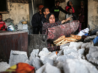 A Palestinian woman is baking traditional bread inside her damaged home in Bureij camp in the central Gaza Strip on November 30, 2023, amid...