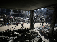 Palestinians are walking amid the rubble of destroyed buildings in Bureij camp in the central Gaza Strip on November 30, 2023, during a truc...