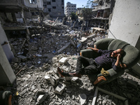 A Palestinian man is sitting inside his damaged home in Bureij camp in the central Gaza Strip on November 30, 2023, amid a truce in fighting...