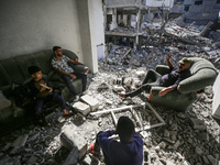 Palestinians are sitting inside their damaged home in Bureij camp in the central Gaza Strip on November 30, 2023, amid a truce in fighting b...
