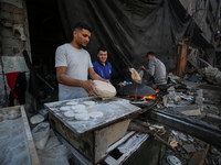 Palestinian workers are making bread in a different location near the former spot of Al-Maghazi bakery, which was heavily damaged in an Isra...