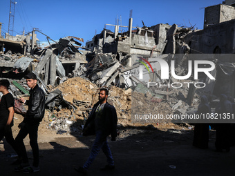 Palestinians are walking in front of Al-Maghazi bakery, which was destroyed in an Israeli strike earlier this month, in Al-Maghazi camp in t...
