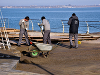 Men are sweeping the embankment at the Lanzheron beach in Odesa, southern Ukraine, on November 30, 2023, after it was damaged in a storm. NO...