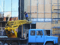 A construction worker is boarding up smashed windows at an office building that has been damaged by Russian shelling in Kharkiv, Ukraine, on...
