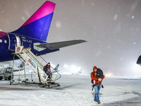 Passengers disembark a plane after flight delay due to heavy snow at Krakow Airport in Balice, Poland on December 2rd, 2023. Intense snowfal...