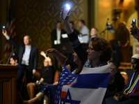 Attendees are holding up flags and phones while Governor Josh Shapiro and Senator Bob Casey join local community leaders in rallying against...