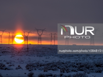 A high-voltage power line is being seen at sunset amid extreme cold weather of minus 20 degrees Celsius in Karamay, Xinjiang, China, on Dece...