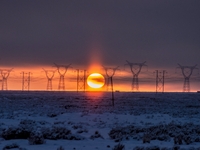 A high-voltage power line is being seen at sunset amid extreme cold weather of minus 20 degrees Celsius in Karamay, Xinjiang, China, on Dece...