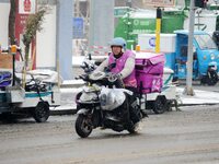 A courier is riding during heavy snow in Beijing, China, on December 14, 2023. (