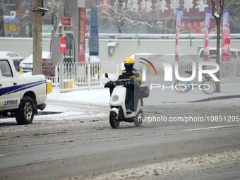 A courier is riding during heavy snow in Beijing, China, on December 14, 2023. (