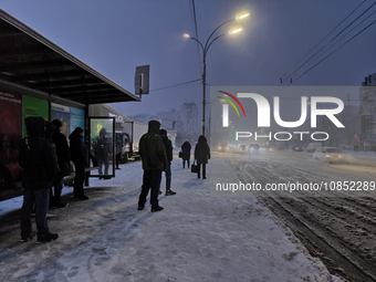 People are waiting at a public transport stop during a snowfall in Kyiv, Ukraine, on December 14, 2023. (