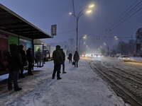 People are waiting at a public transport stop during a snowfall in Kyiv, Ukraine, on December 14, 2023. (