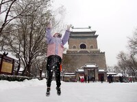 Tourists are playing in the snow at the Bell and Drum Tower Square in Beijing, China, on December 14, 2023. (
