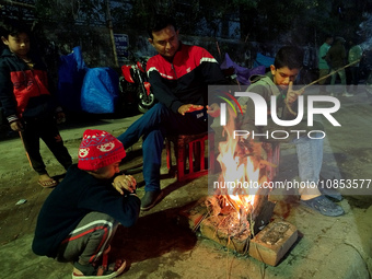 People are sitting next to a bonfire in an open space on a cold winter night in Kolkata, India, on December 14, 2023. (