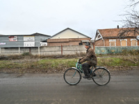 A man is riding a bicycle past houses that have been damaged by Russian shelling in Orikhiv, Zaporizhzhia Region, southeastern Ukraine, on D...