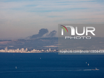 Clouds of smoke are billowing from Israel's northern port city of Haifa on the Mediterranean Coast, and an Israeli naval warship is sailing...