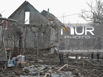 People are standing outside a house that has been damaged by Russian shelling in the Odesa Region, southern Ukraine, on December 17, 2023. (