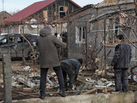 People are standing outside a house that has been damaged by Russian shelling in the Odesa Region, southern Ukraine, on December 17, 2023. (