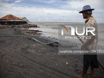 Carmat (83) is walking on the beach near the remains of his house, which was destroyed by high waves in Cemarajaya Village, Karawang Regency...