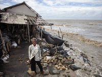 Carmat, 83, is posing for a photo near his house, which was destroyed by high waves in Cemarajaya Village, Karawang Regency, West Java Provi...