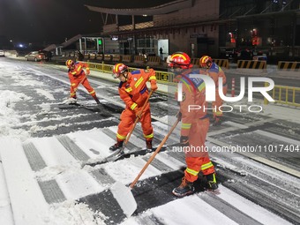 Fire and rescue workers are clearing snow from a road in Taizhou, Jiangsu Province, China, on February 23, 2024. (