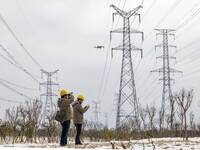 A staff member of a power supply company is using a drone to inspect the ice covering on power lines in Taizhou, Jiangsu Province, China, on...
