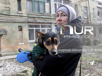 A woman is holding a dog near a block of flats that was hit by a Russian Shahed drone during an overnight attack in Dnipro, Ukraine, on Febr...