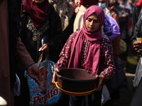 Displaced Palestinians are gathering to receive food at a donation point in Deir al-Balah, central Gaza Strip, on February 24, 2024, amid co...