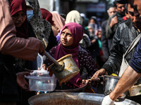Displaced Palestinians are waiting to receive food cooked by a charity kitchen amid shortages of food supplies as the ongoing conflict betwe...