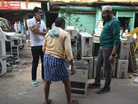 People are inspecting a second-hand air conditioner for purchase inside a second-hand electronics market in Kolkata, India, on February 26,...