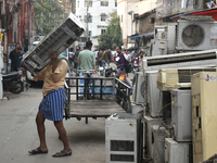 A person is carrying a second-hand air conditioner inside a second-hand electronics market in Kolkata, India, on February 26, 2024. (