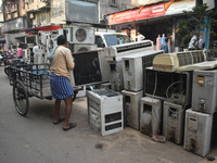 A person is loading a second-hand air conditioner onto his tricycle at a second-hand electronics market in Kolkata, India, on February 26, 2...
