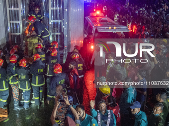 Firefighters are carrying an injured person during a rescue operation after a fire broke out in a commercial building in Dhaka, Bangladesh,...