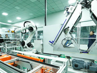 A staff member is observing the operation of an energy storage module robot on an automated production line for manufacturing energy storage...